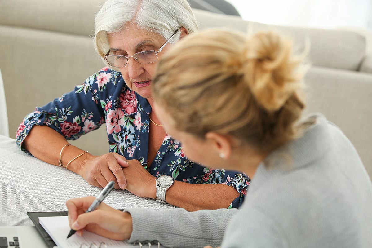 Woman helping elder woman with debt